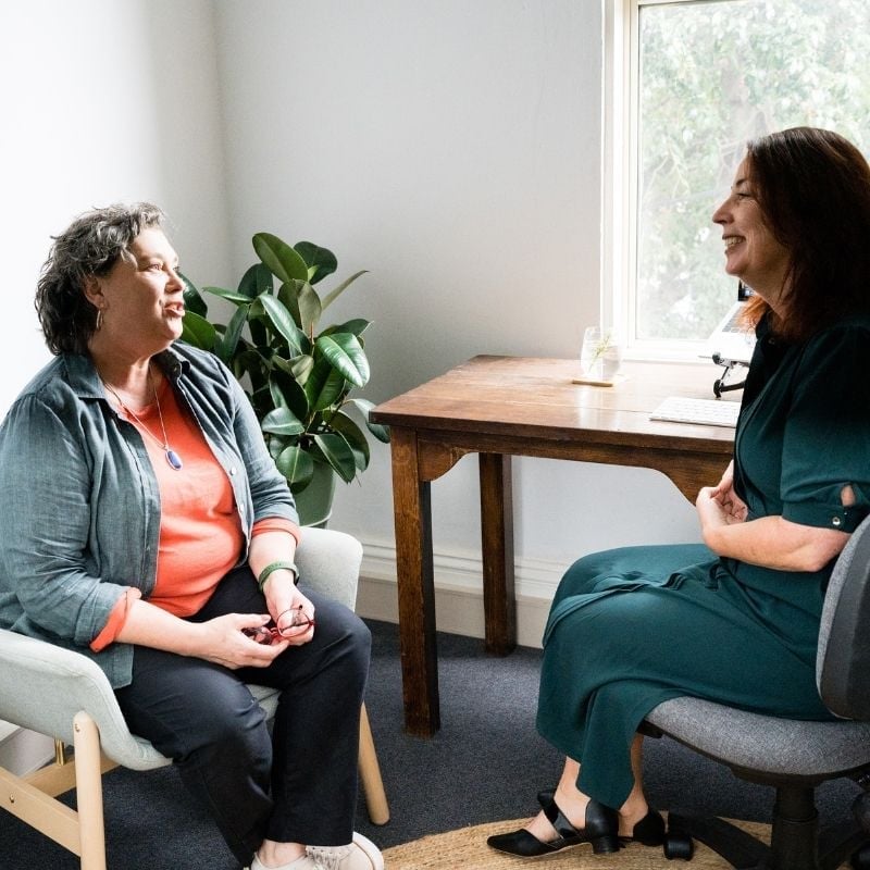 female practitioner sitting in clinic with patient pointing to results on printed report