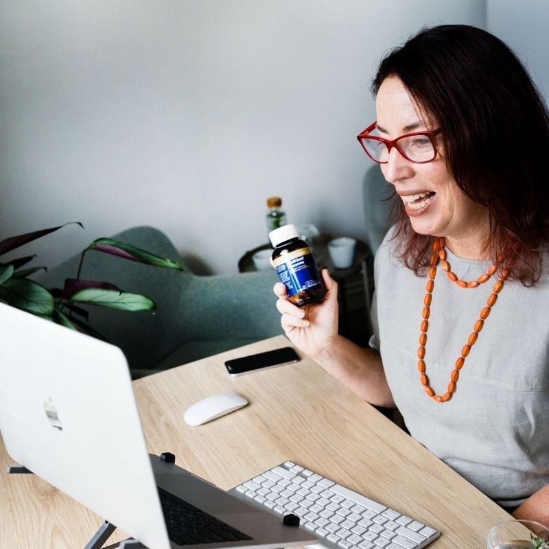 female smiling wearing orange dress on health coaching telehealth via laptop