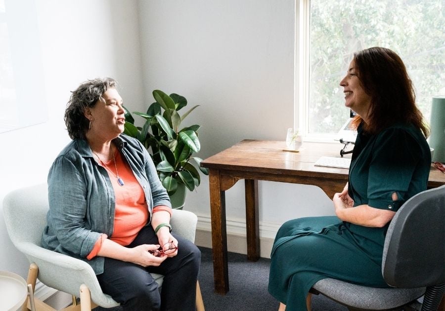 female practitioner sitting in clinic with patient pointing to results on printed report