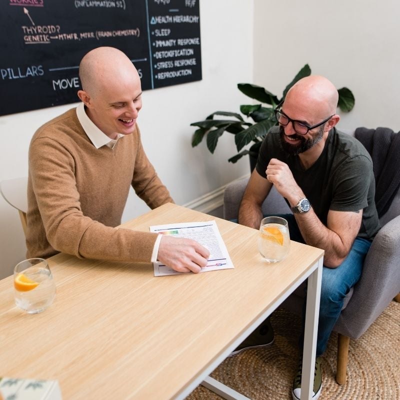 practitioner jabe and health coach bee sitting on a couch discussing lab results.