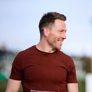 fit man standing outside looking sideways smiling