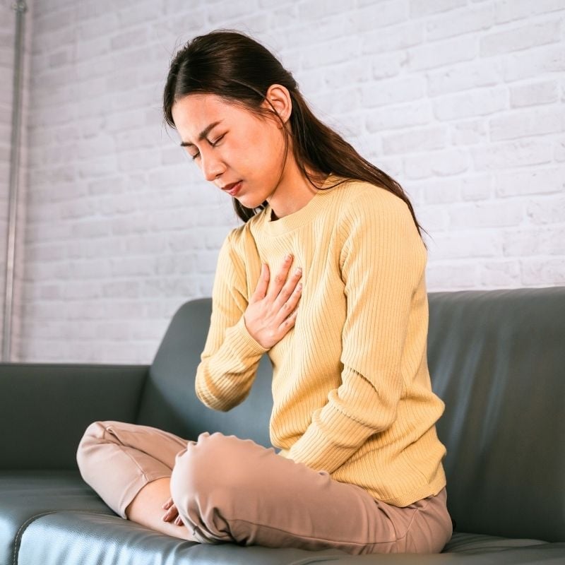 acid-reflux-functional-medicine-condition middle aged woman with acid reflux heartburn pressing palm of hand to upper chest