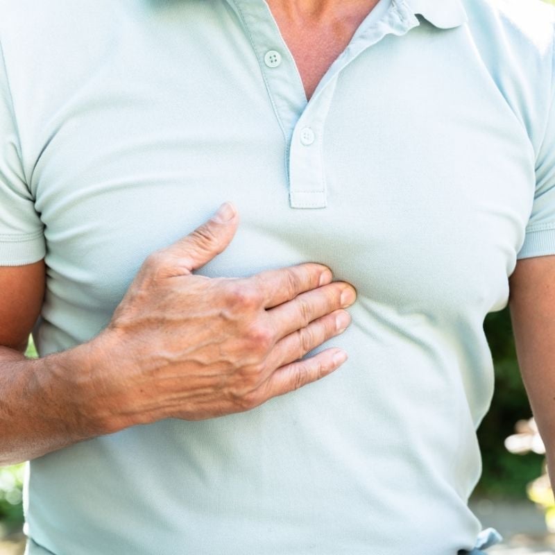 acid-reflux-functional-medicine-hero middle aged man with acid reflux heartburn pressing fingers into centre of chest