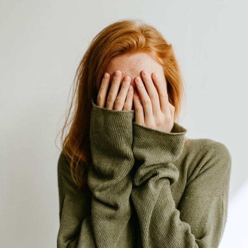 acne-functional-medicine-hero young woman with acne covering her face with both hands