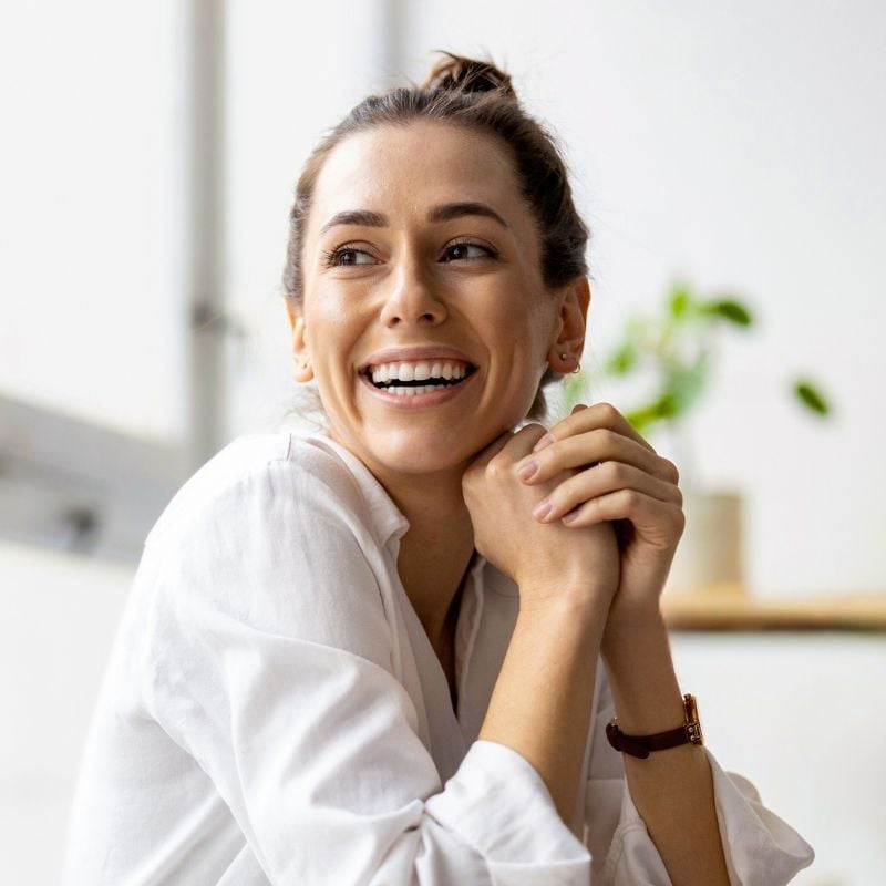 adelaide-functional-medicine-hero middle aged woman vibrant healthy smiling sitting hands clasped near face