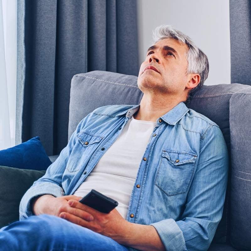 atrial-fibrillation-functional-medicine-condition middle aged man leaning back on couch looking at ceiling contemplative expression