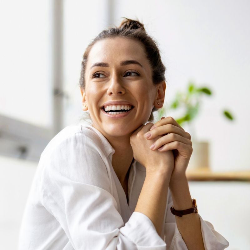 australia-functional-medicine-hero middle aged woman vibrant healthy smiling sitting hands clasped near face