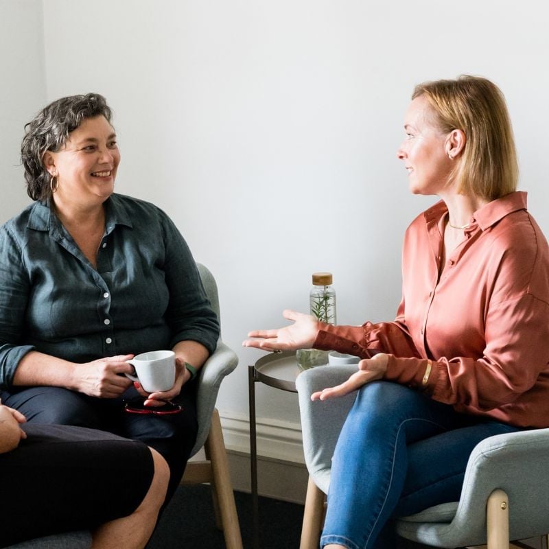 results-focused-collaborative-approach practitioner jabe and health coach bee sitting on a couch discussing lab results.