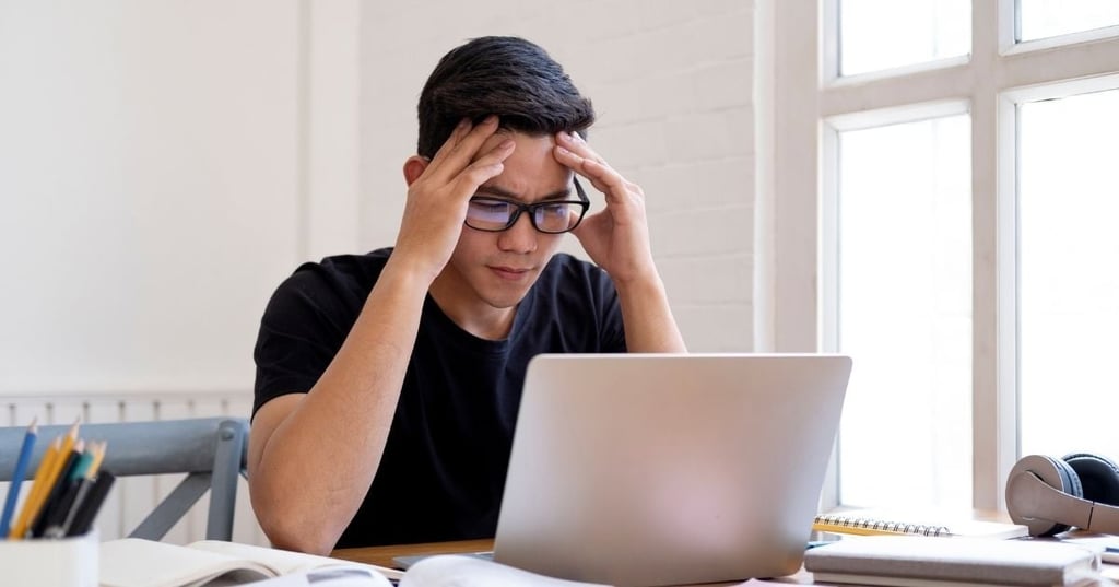 brain-fog-brain-health man sitting at desk in front of lap top resting head in hands
