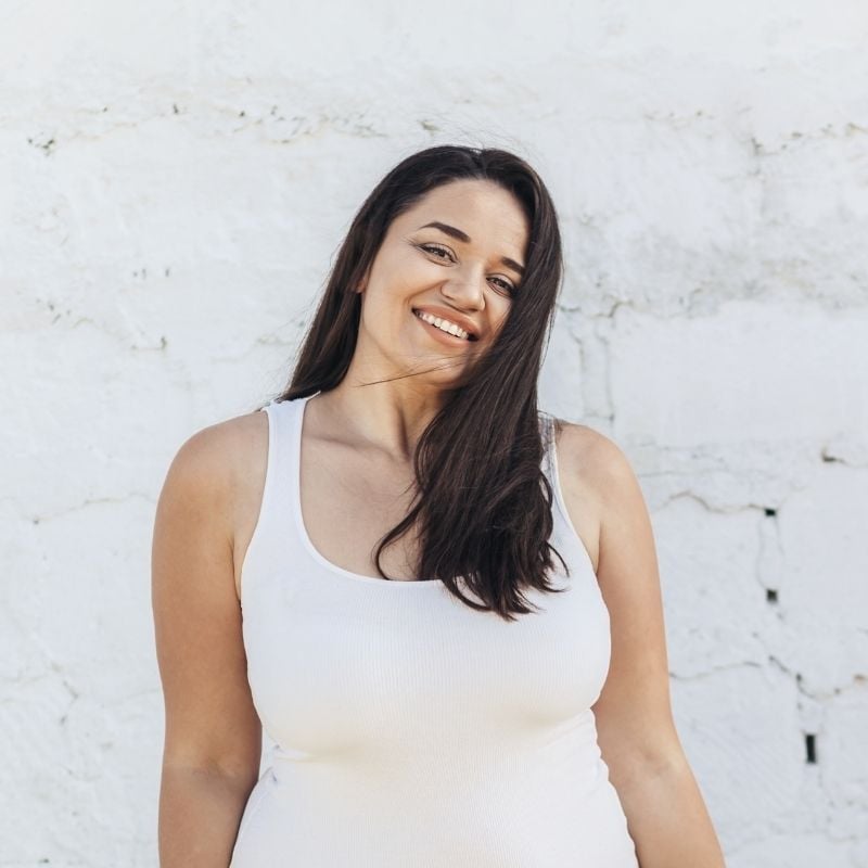 candida-functional-medicine-root-cause young woman standing against white brick wall in warm weather smiling