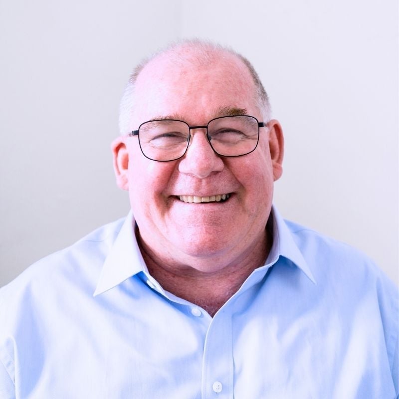 cardiovascular-disease-functional-medicine-hero front profile older man smiling wearing plain blue shirt and glasses