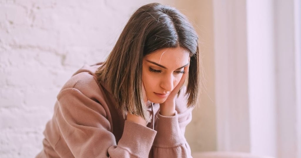 woman sitting down with head resting in hand and concerned look on her face
