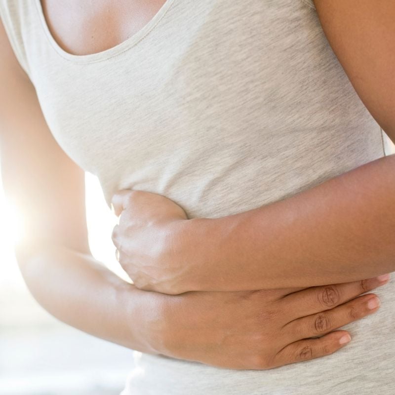 coeliac-functional-medicine-hero middle aged woman with coeliac disease gut pain wrapping arms across front of stomach