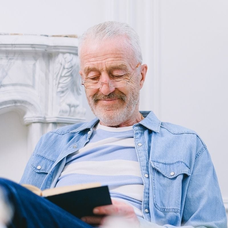 mature man sitting reading book with slight smile