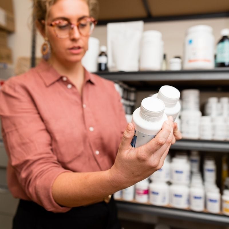 melbourne functional medicine team member holding probiotic supplements reading labels