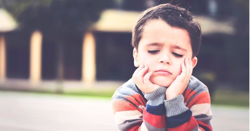 emotional-intelligence-ok-to-feel-sad-hero young boy lying on tummy feeling sad head resting in hands