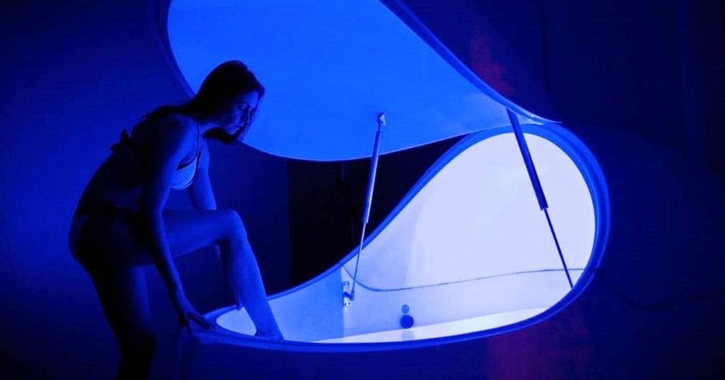 floatation-tanks-hero young woman stepping into floatation tank in dimly lit room