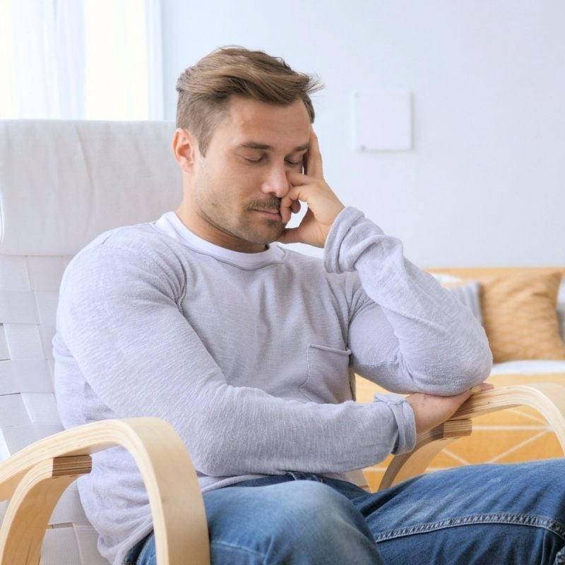 high-cholesterol-functional-medicine-condition middle aged man sitting in armchair with eyes closed head propped up with hand