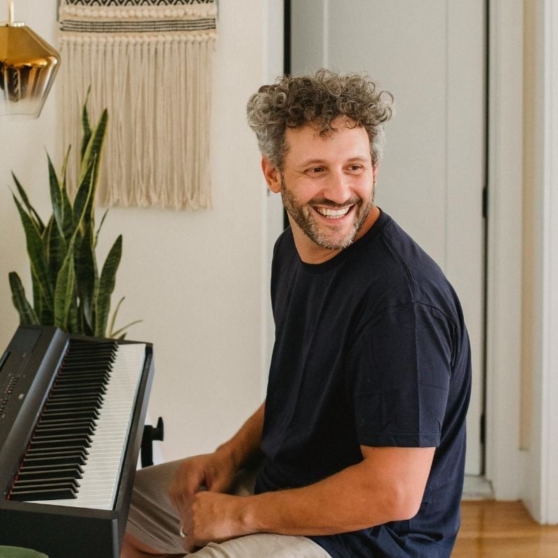 high-cholesterol-functional-medicine-root-cause middle aged man sitting in lounge room at black piano smiling
