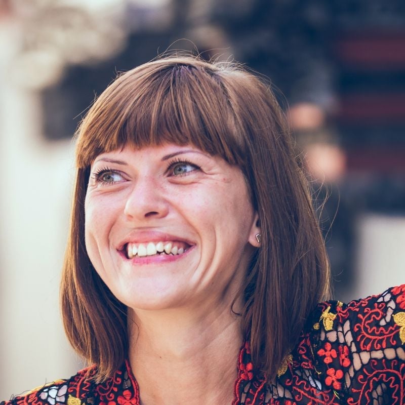 woman wearing patterned shirt straight fringe haircut outside smiling