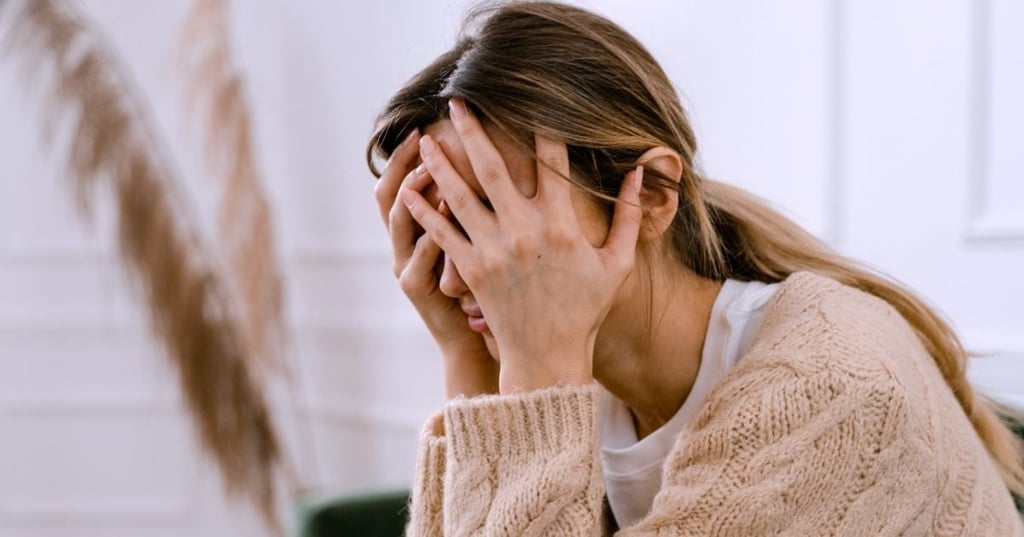 woman seated with head resting in hands covering face