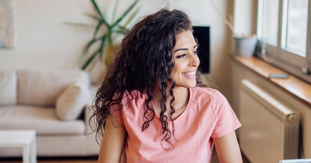 hyperthyroidism-graves-disease-functional-medicine vibrant young woman long curly hair smiling looking out the window