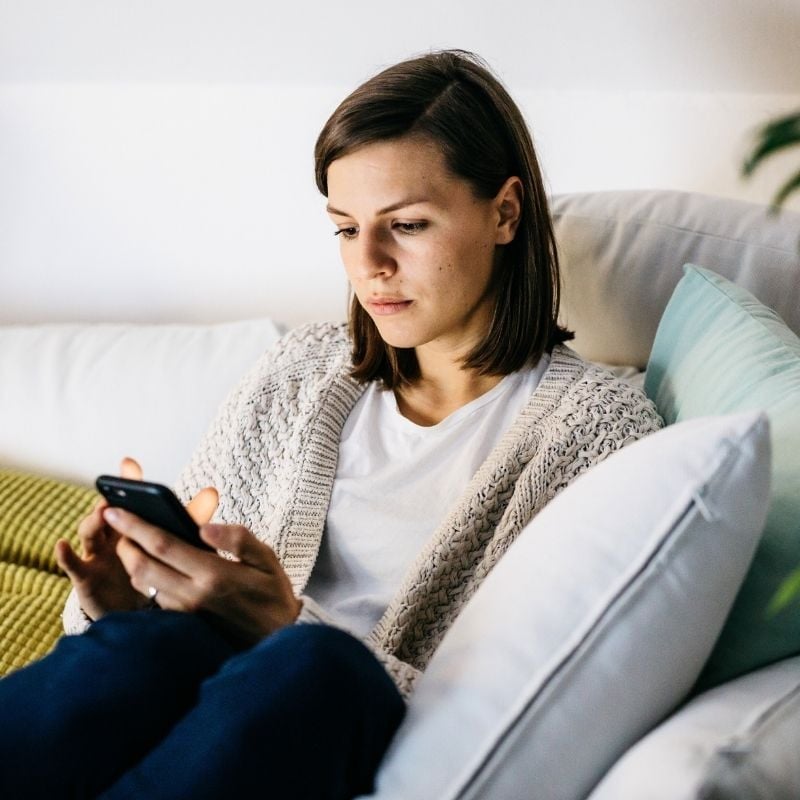 hypotension-functional-medicine-hero middle aged woman with hypotension looking fatigued scrolling through mobile phone