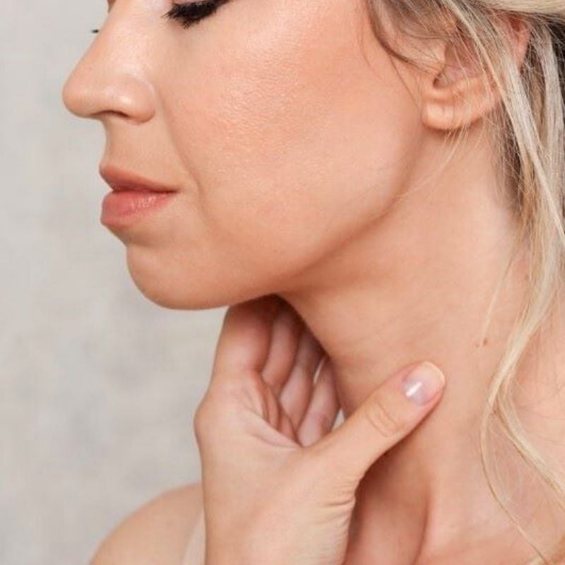 side profile middle aged woman look downward holding front of neck