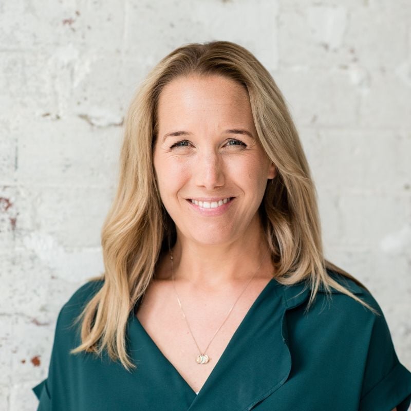 jessica cairns health coach wearing dark green shirt standing smiling