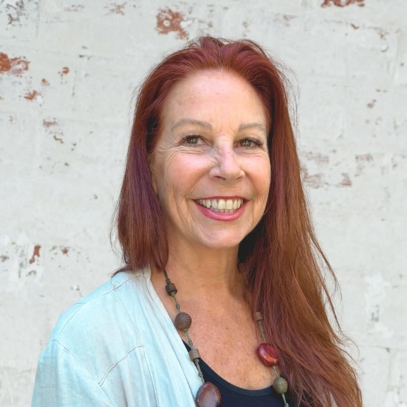 functional medicine practitioner standing in front of white brick wall smiling