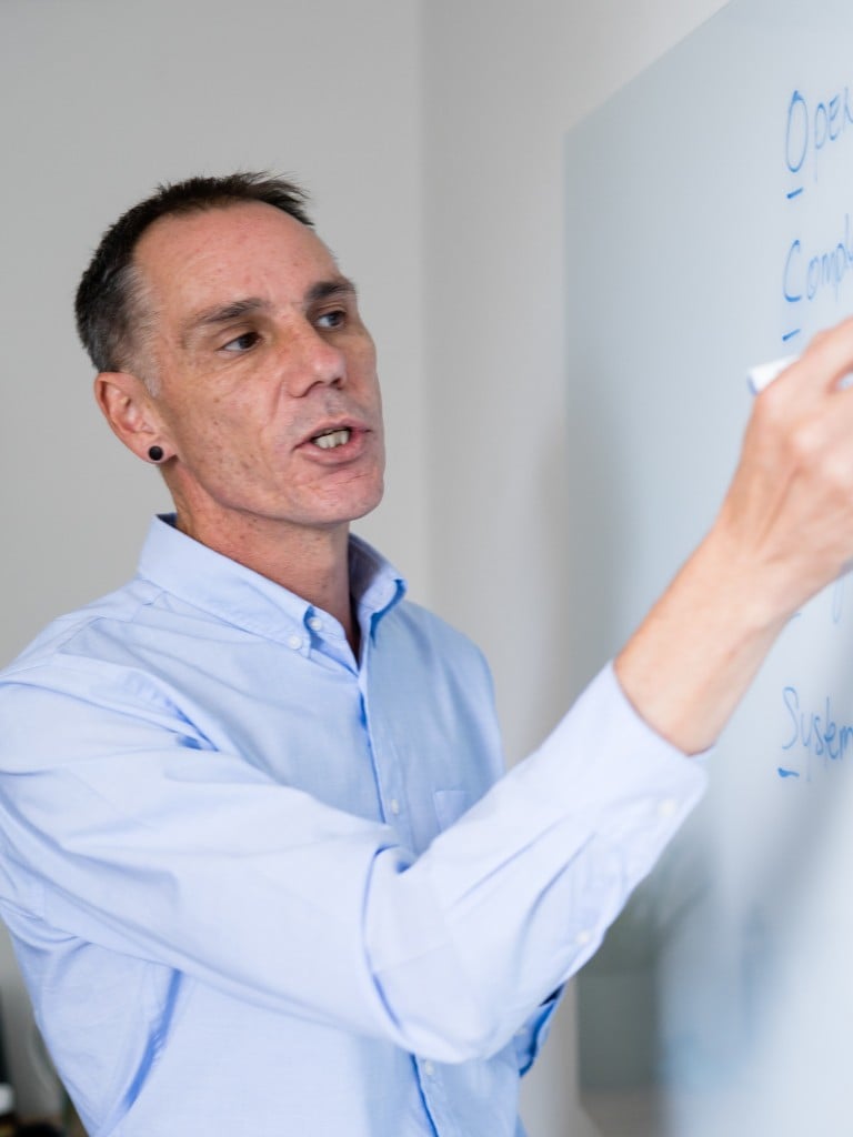 male functional medicine practitioner standing writing on whiteboard