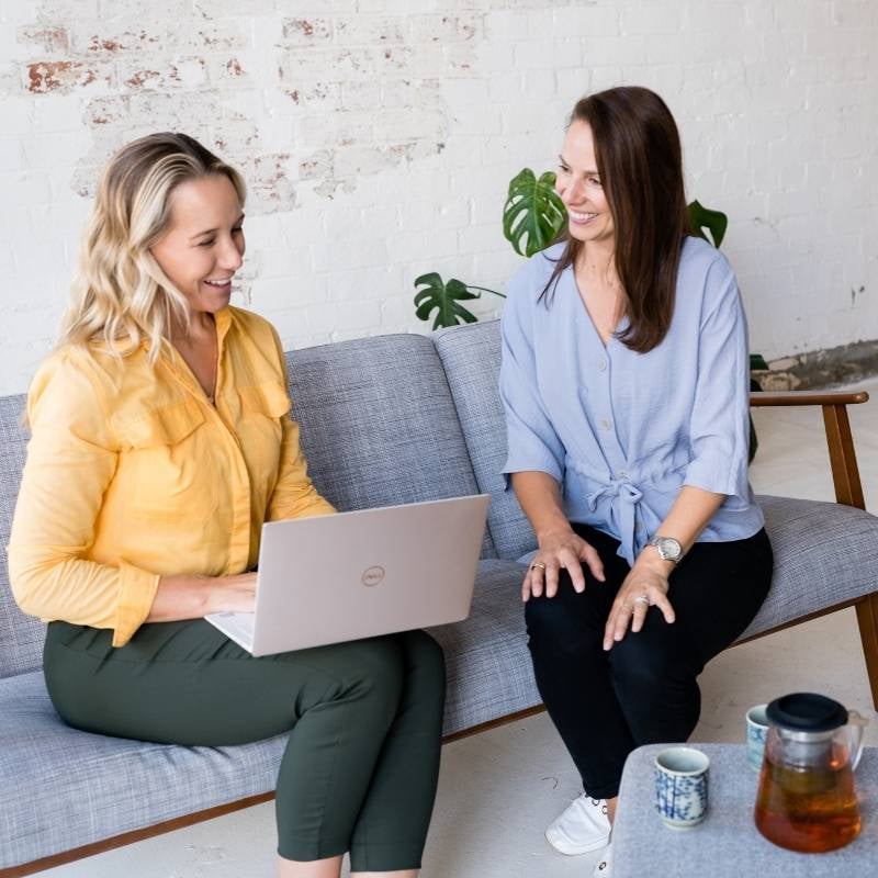 meet-the-team-hero melbourne functional medicine health coaches jessica cairns and liv brown sitting collaborating on laptop