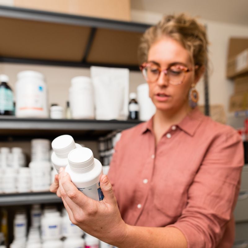 practice manager standing in clinic reading supplement label in dispensary