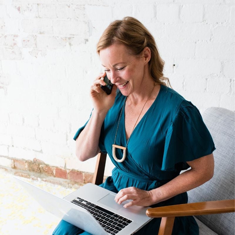 bee pennington health coach smiling sitting in armchair laptop on lap talking with patient on mobile phone