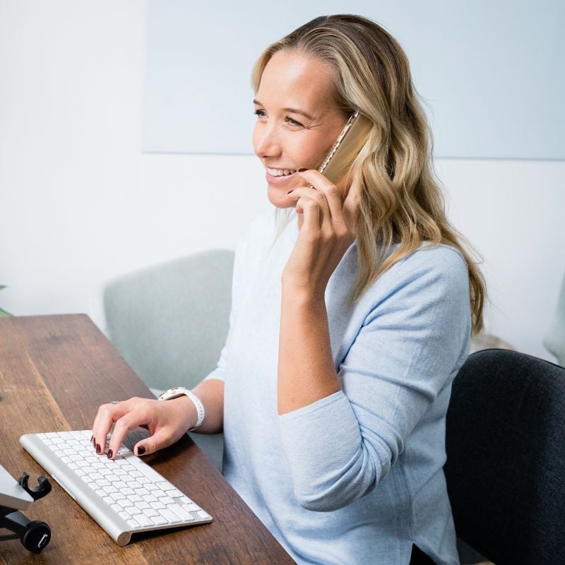 melbourne-functional-medicine-free-discovery-call-hero jessica cairns health coach sitting at desk taking an enquiry call on mobile phone