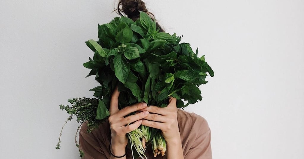 healthy woman holding three big bunches of herbs up in front of face