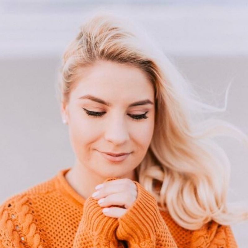 multiple-sclerosis-functional-medicine-root-cause young woman outside wearing orange knit jumper looking down