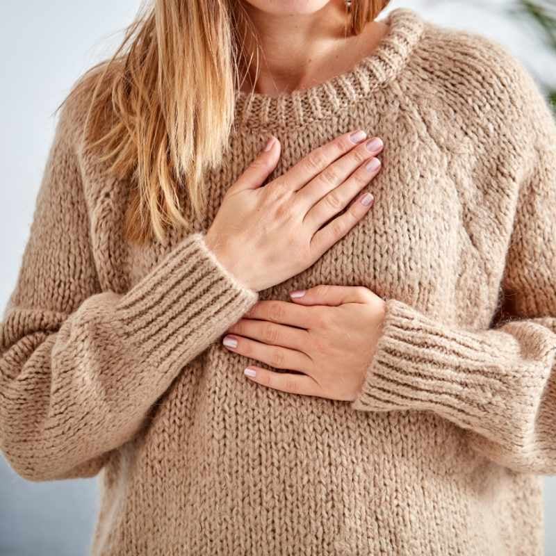 middle aged woman with chest pain holding chest with both hands