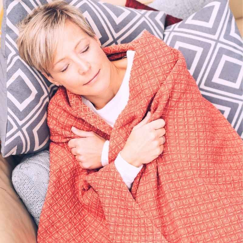 recurrent-uti-functional-medicine-condition middle aged woman lying peacefully on couch eyes closed wrapped in light blanket