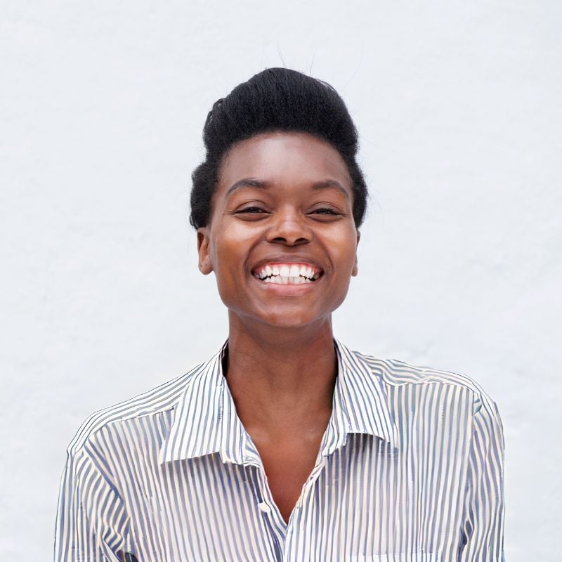 woman standing outside in front of white wall laughing