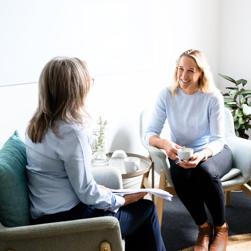 results-focused-collaborative-approach practitioner jabe and health coach bee sitting on a couch discussing lab results.