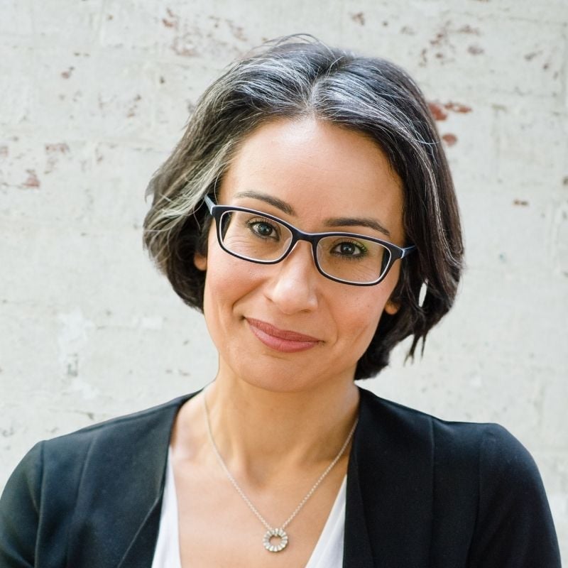 functional medicine practitioner standing in front of white brick wall gentle smile