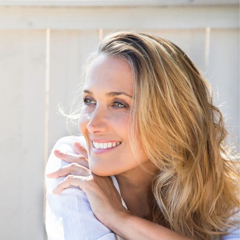 woman in midlife sun on face smiling long hair to the side