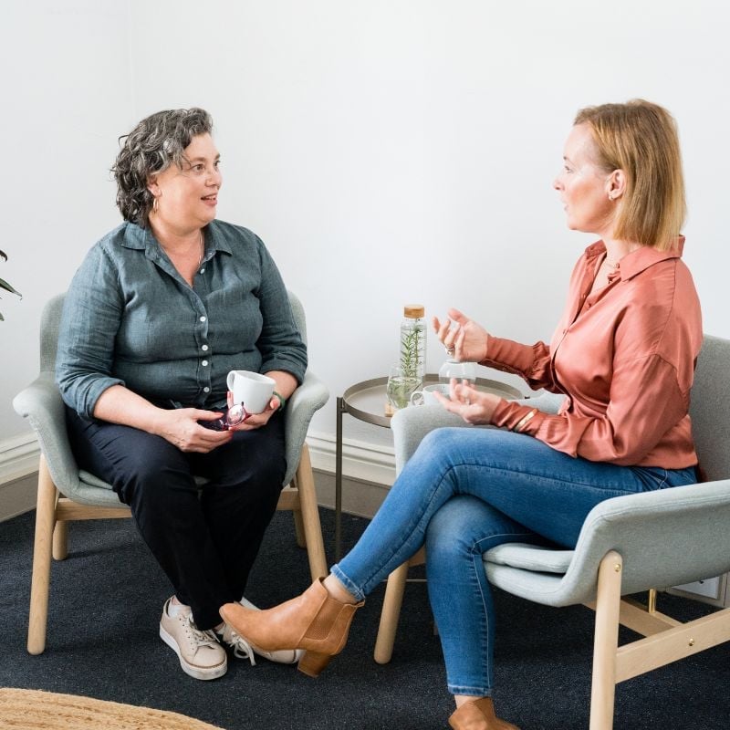 results-focused-collaborative-approach practitioner jabe and health coach bee sitting on a couch discussing lab results.