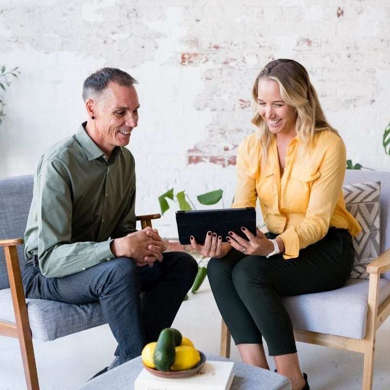 female smiling wearing orange dress on health coaching telehealth via laptop