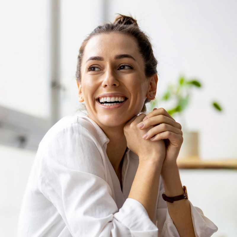 adelaide-functional-medicine-hero middle aged woman vibrant healthy smiling sitting hands clasped near face