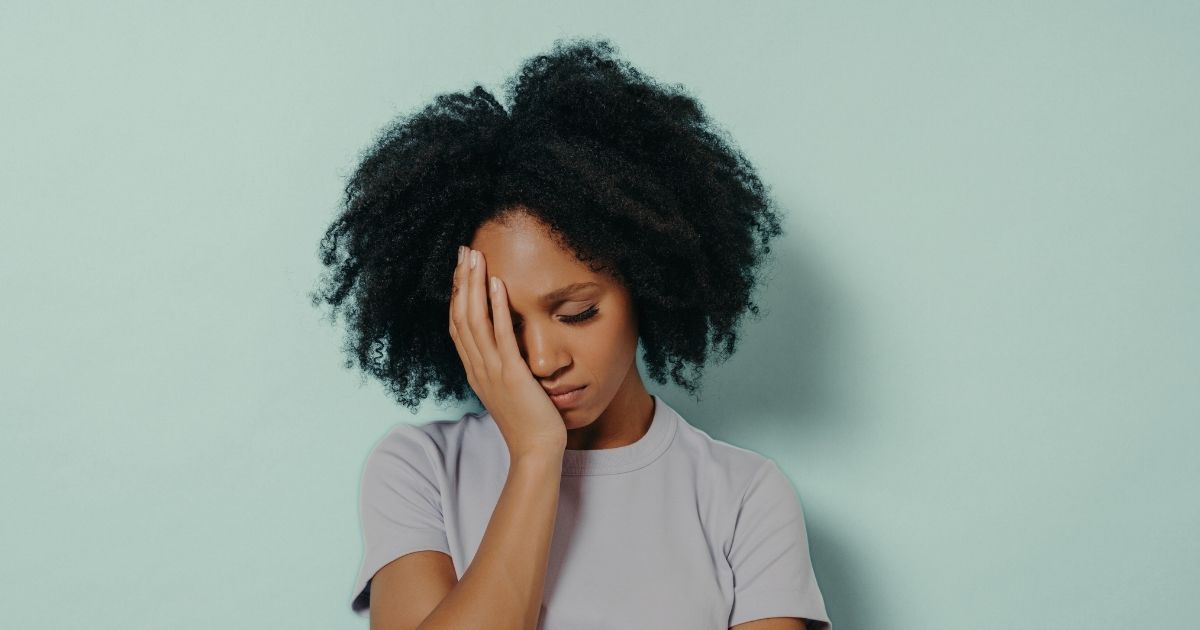 middle aged women leaning forward over bed eyes closed head resting on arm