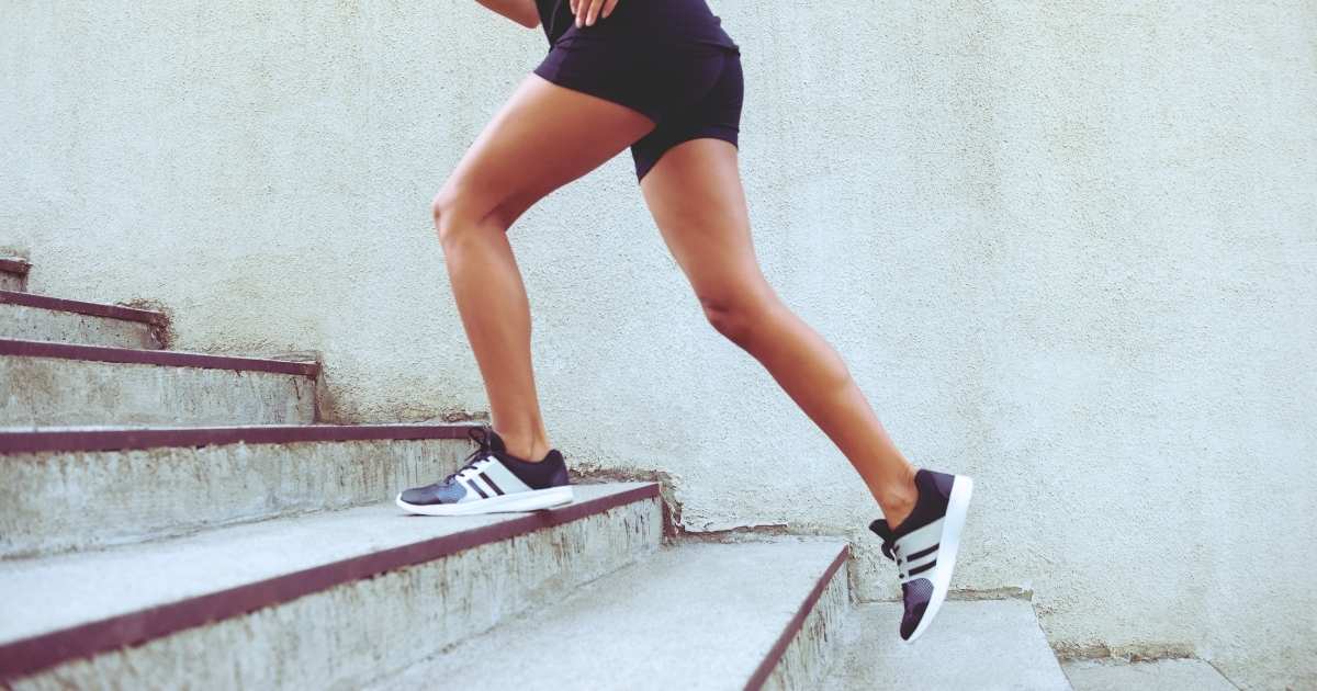 side profile woman in active gear running up concrete outdoor steps