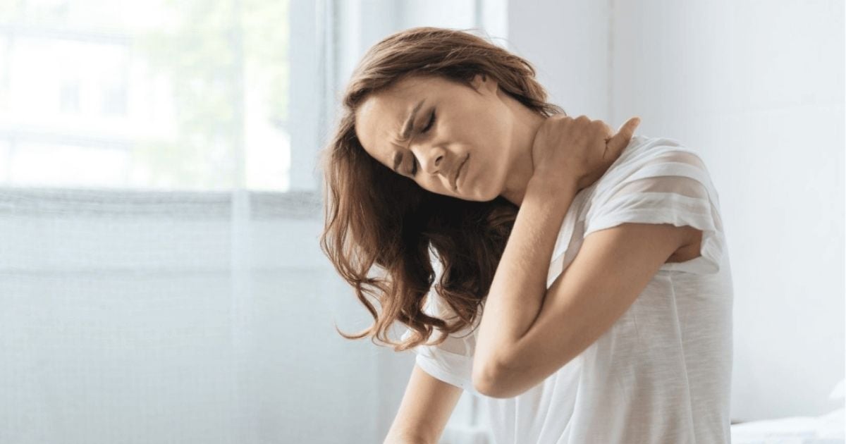 middle aged woman sitting holding back of neck with hand in response to chronic inflammation