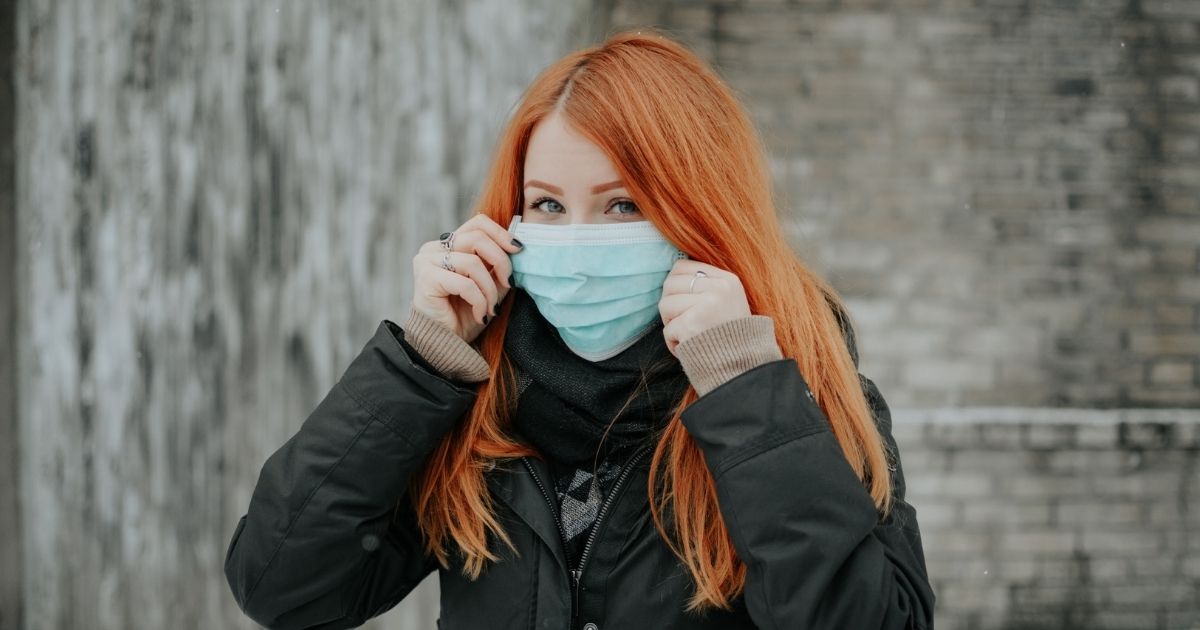 young woman putting on surgical face mask to prevent coronavirus protect her health